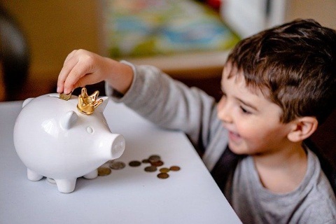 Kind das Geld in ein Sparschwein wirft